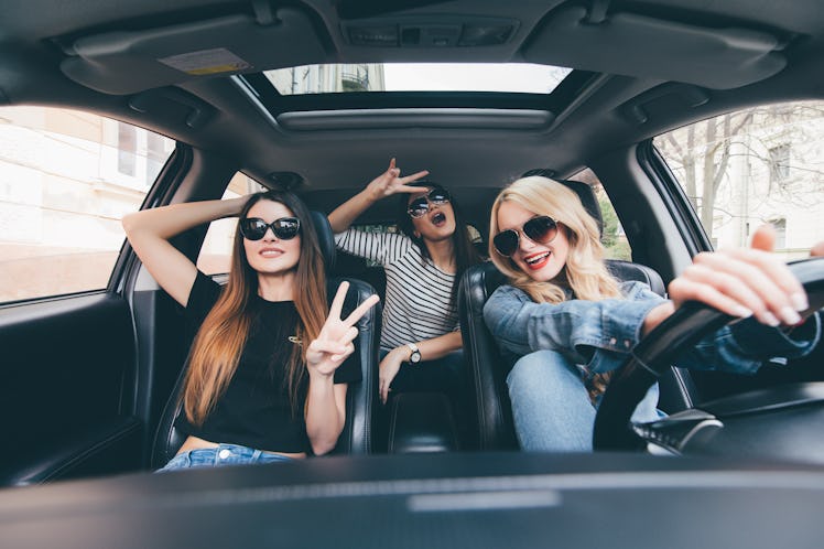 Group of friends having fun on the car. Singing and laughing in the city