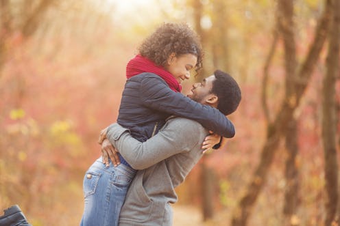 Happy couple in love enjoying autumn day, man holding girlfriend on hands, walking in park