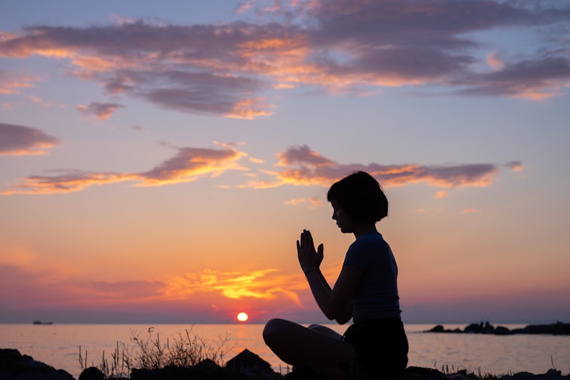 Sunset view of isolated woman meditating