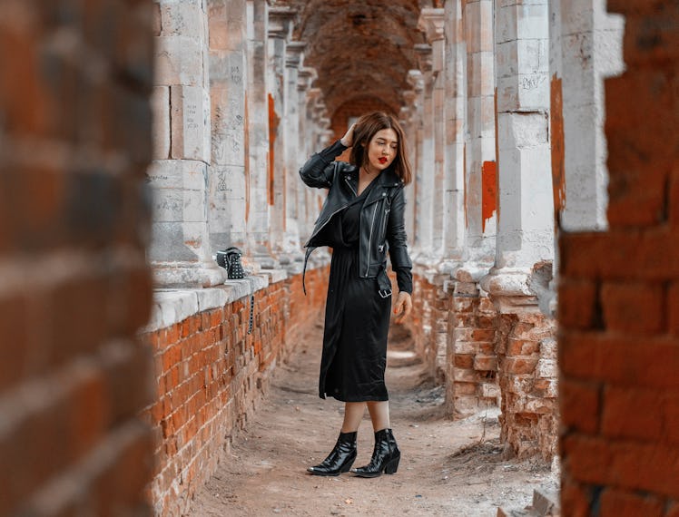 Young beautiful brunette woman in black dress posing at ancient ruins. Modern bloffer and explorer. ...