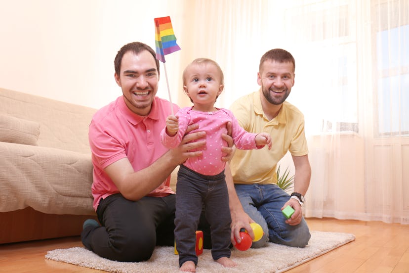 Male gay couple with adopted baby girl at home