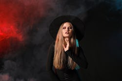 Beautiful woman dressed as witch for Halloween on dark background
