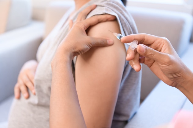 Doctor put needle in muscular for flu shot immunization to pregnant women.