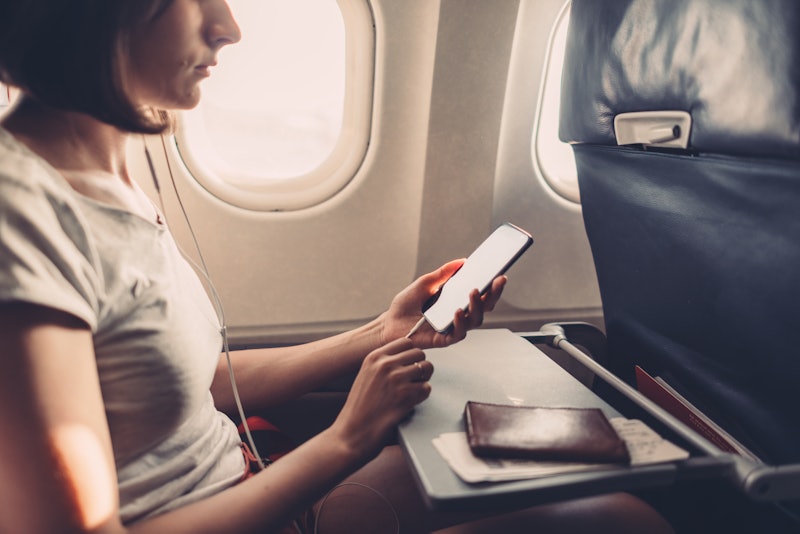 Young woman on a plane with a smartphone in her hands
