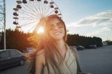 woman smiling cheerfully in front of a ferris wheel