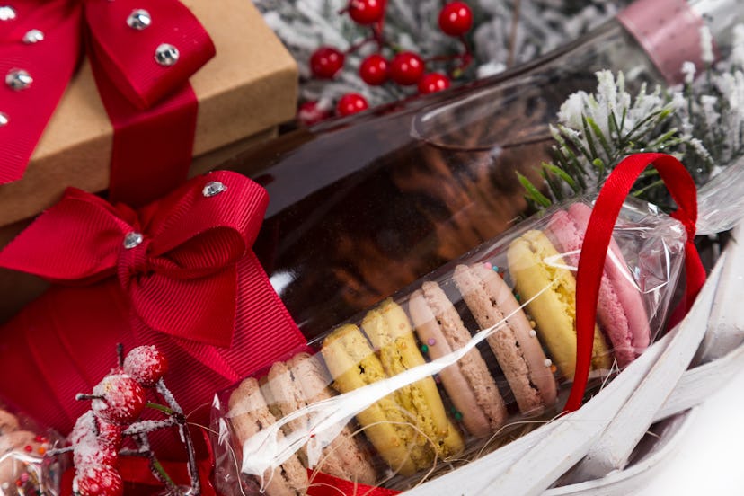 christmas present in basket with sweet pastry, bottle of wine and decor