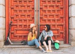 Young women lesbian couple looking and smiling each other in a red door background. Same sex happine...