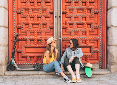 Young women lesbian couple looking and smiling each other in a red door background. Same sex happine...