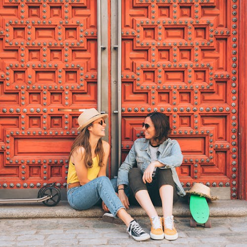 Young women lesbian couple looking and smiling each other in a red door background. Same sex happine...