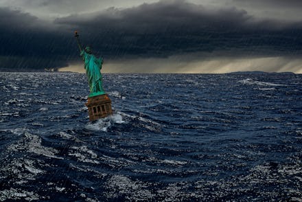 Surreal apocalyptic scene with The Statue of Liberty sinks in the ocean in the sunset under the dram...