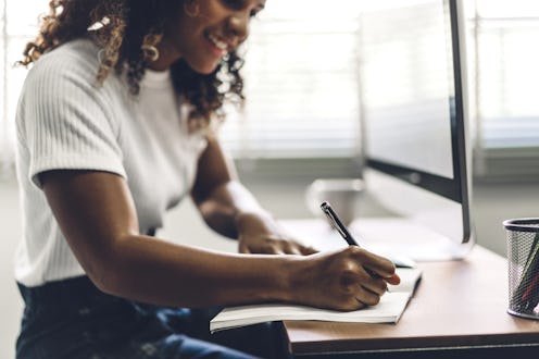 A Black woman sits at her desk. Workplace burnout can be reduced by talking about your mental health...