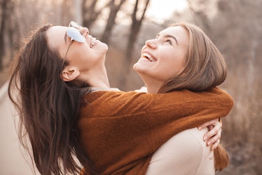Two young women laughing and hugging outside in the fall are striking a great pose for fall puns for...
