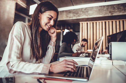Portrait of beautiful young woman working in the office. Side view