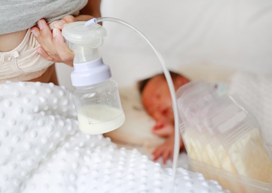 mom with breast pump and newborn baby in background