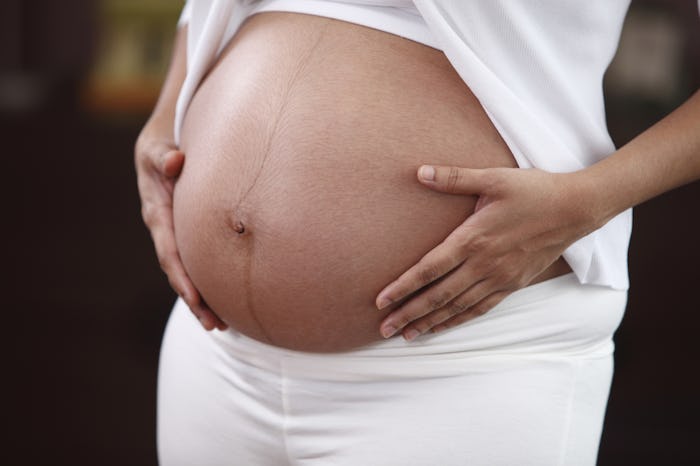 Belly of a pregnant woman with her hands on it