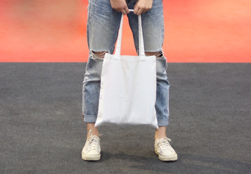 model hold blank white fabric tote bag for saving the environment on street fashion