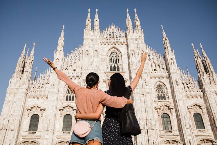 Two stylish best friends pose in front of the Duomo in Milan, Italy, during a holiday trip.