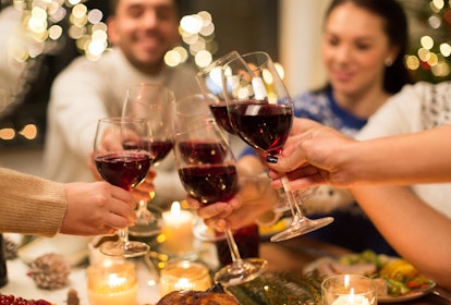 holidays and celebration concept - close up of happy friends having christmas dinner at home, drinki...