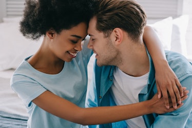 Young woman embracing boyfriend while sitting on bed