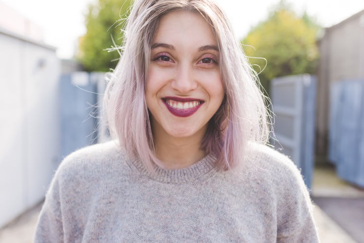 Portrait of young beautiful caucasian purple grey hair woman outdoor in the city looking at camera, ...
