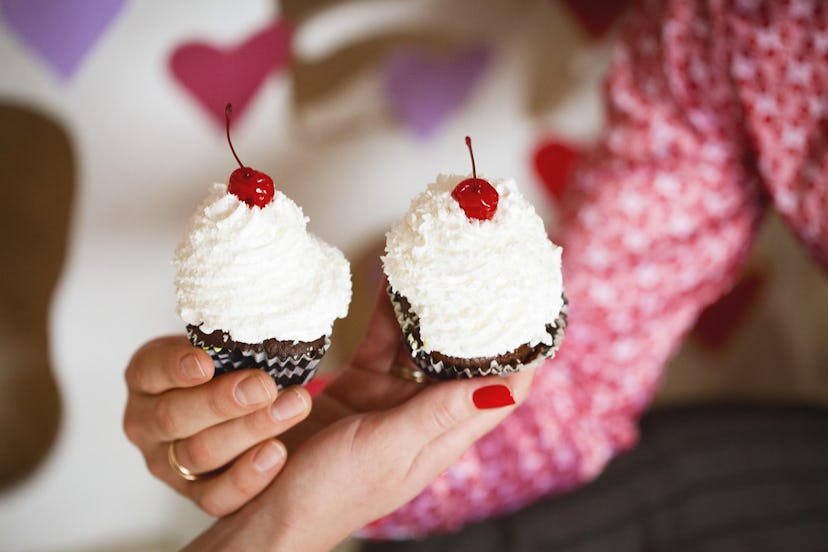 Cupcakes with whipped cream and cherry in hands