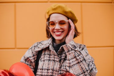 A stylish girl poses for a colorful Instagram picture in orange sunglasses while on a trip.