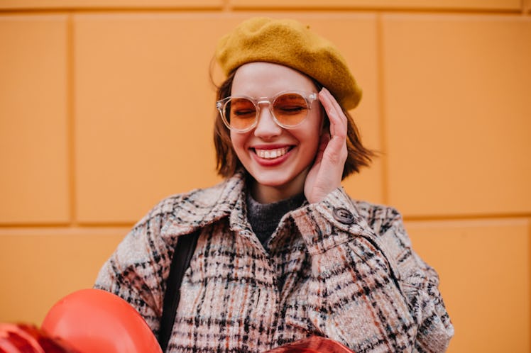 A stylish girl poses for a colorful Instagram picture in orange sunglasses while on a trip.