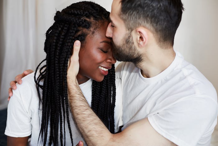 International couple. African American girl and white man hugging on bed