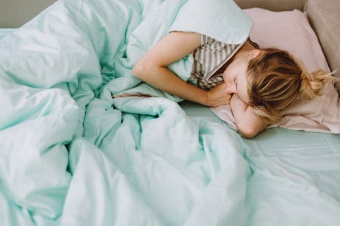 Woman sleeping in bed with her eyes closed. She is resting on a pillow