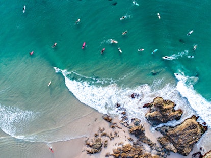 An aerial view of Byron Bay, Australia shows kayakers and surfers in the water.
