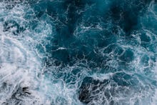 Aerial view to ocean waves. Blue water background