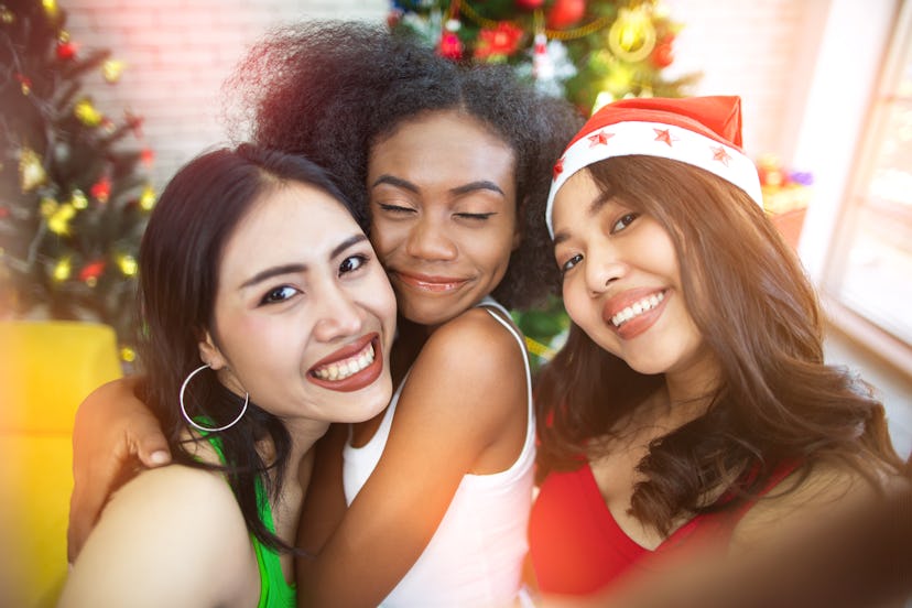 Three happy and beautiful girls taking selfie while celebrating in Christmas party at home