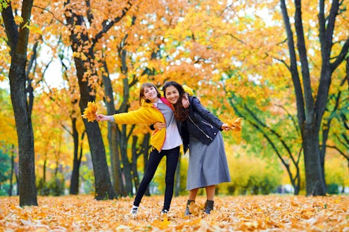 woman having fun with autumn leaves in city park, outdoor portrait
