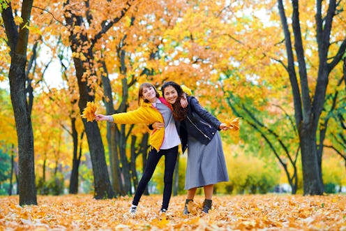 woman having fun with autumn leaves in city park, outdoor portrait