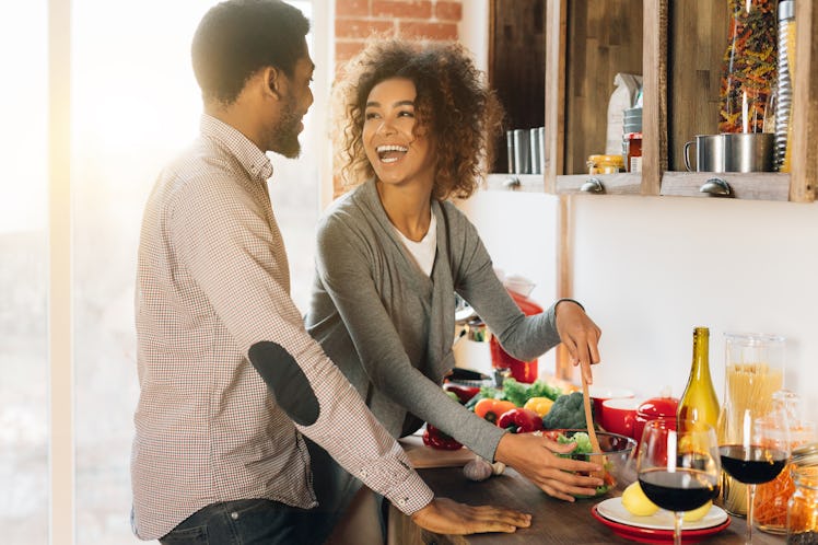 A happy couple prepares dinner in their kitchen.