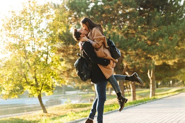Image of a happy young beautiful loving couple posing walking outdoors in park nature kissing.