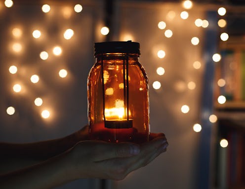 kids holds Christmas lantern in hands on lights bokeh background. New year celebration concept, fest...