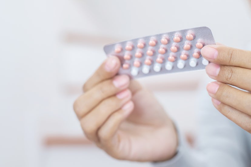 Woman hands opening birth control pills in hand. eating Contraceptive pill. Contraception reduces ch...