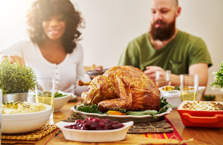 interacial couple eating thanksgiving dinner with focus on turkey