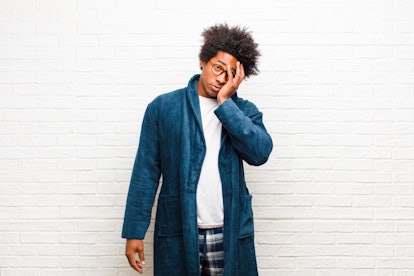 young black man wearing pajamas with gown feeling bored, frustrated and sleepy after a tiresome, dul...