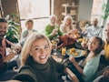 Selfie of a big family sitting around a table for Thanksgiving dinner to post to Instagram with the ...