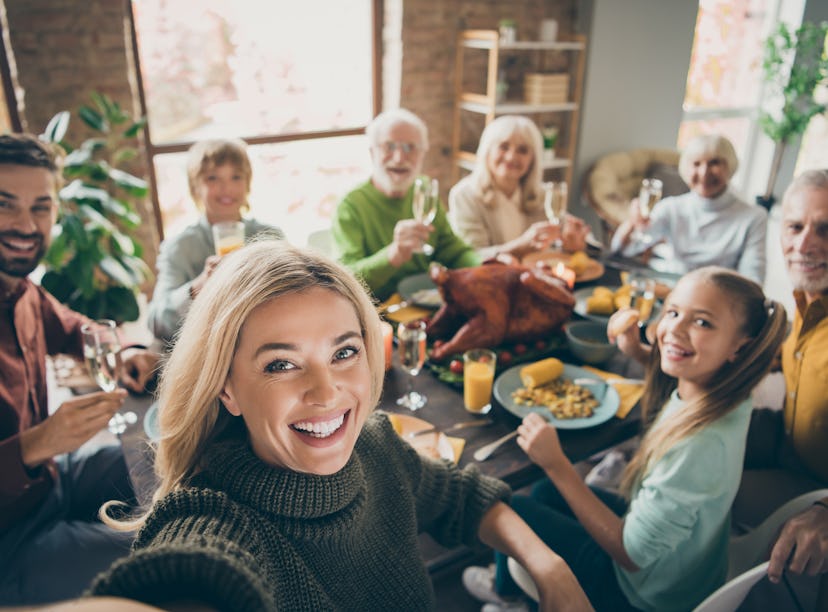 Selfie of a big family sitting around a table for Thanksgiving dinner to post to Instagram with the ...