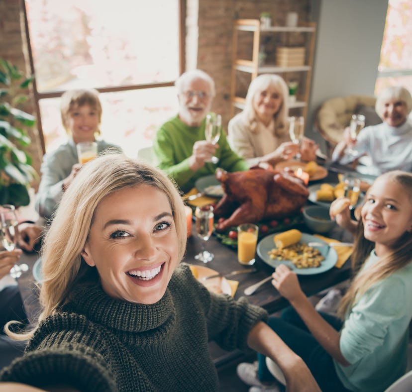 Selfie of a big family sitting around a table for Thanksgiving dinner to post to Instagram with the ...