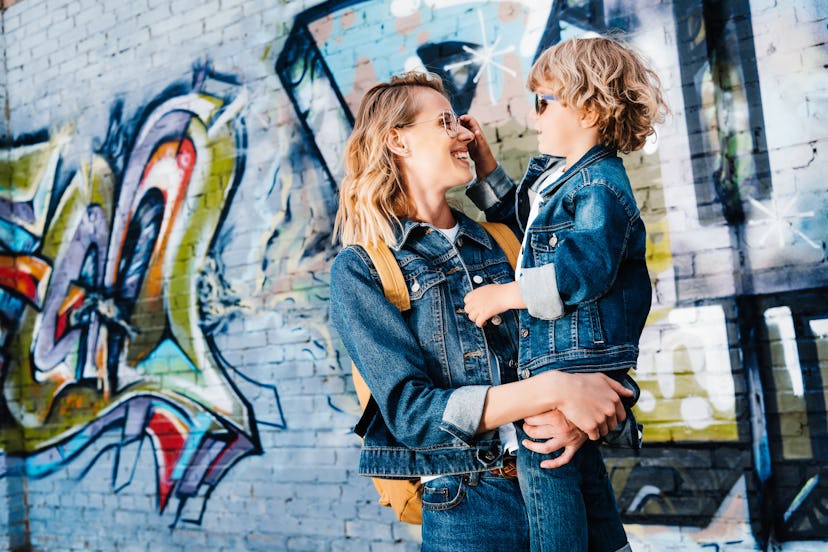 happy mother holding son and they looking at each other on street