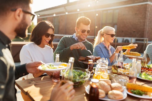 leisure and people concept - happy friends eating and drinking at barbecue party on rooftop in summe...