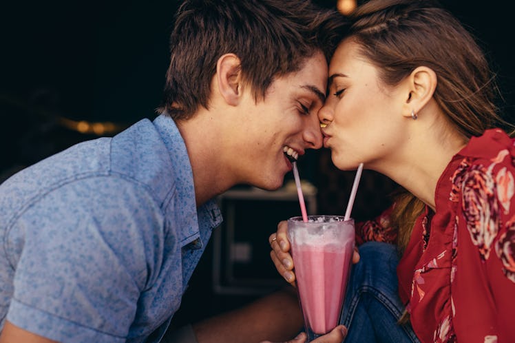 Woman kissing her boyfriend on his nose while on date at a restaurant. Couple at a restaurant in rom...