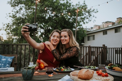 A couple takes a selfie on a camera while eating Thanksgiving dinner outside.