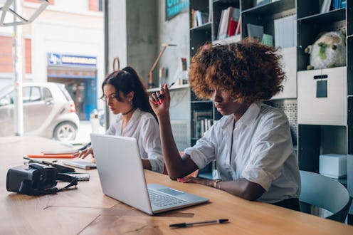 two young multiracial women writing and working with digital device in modern coworking space – free...