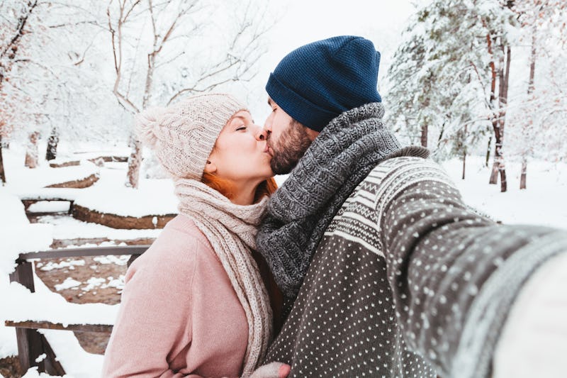 Young couple taking a selfie in a park on a snowy day