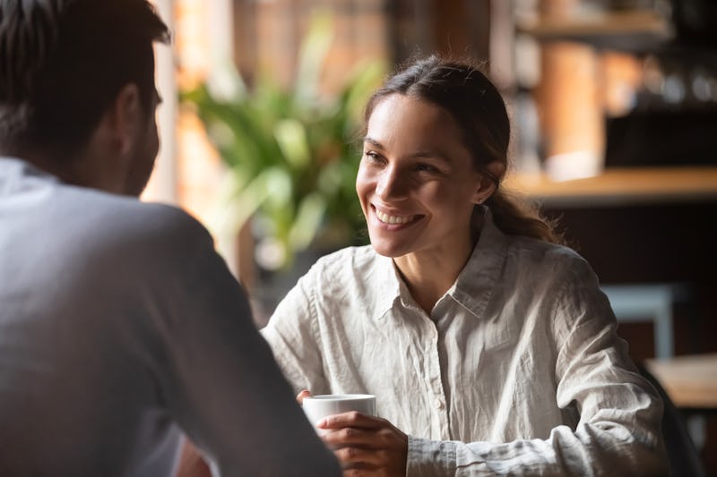 Smiling young woman talking to male friend boyfriend at meeting or romantic date in cafe, happy pret...